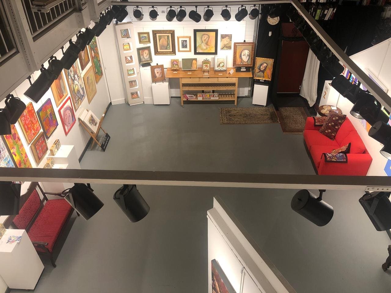 An aerial view of an art gallery with a red couch.