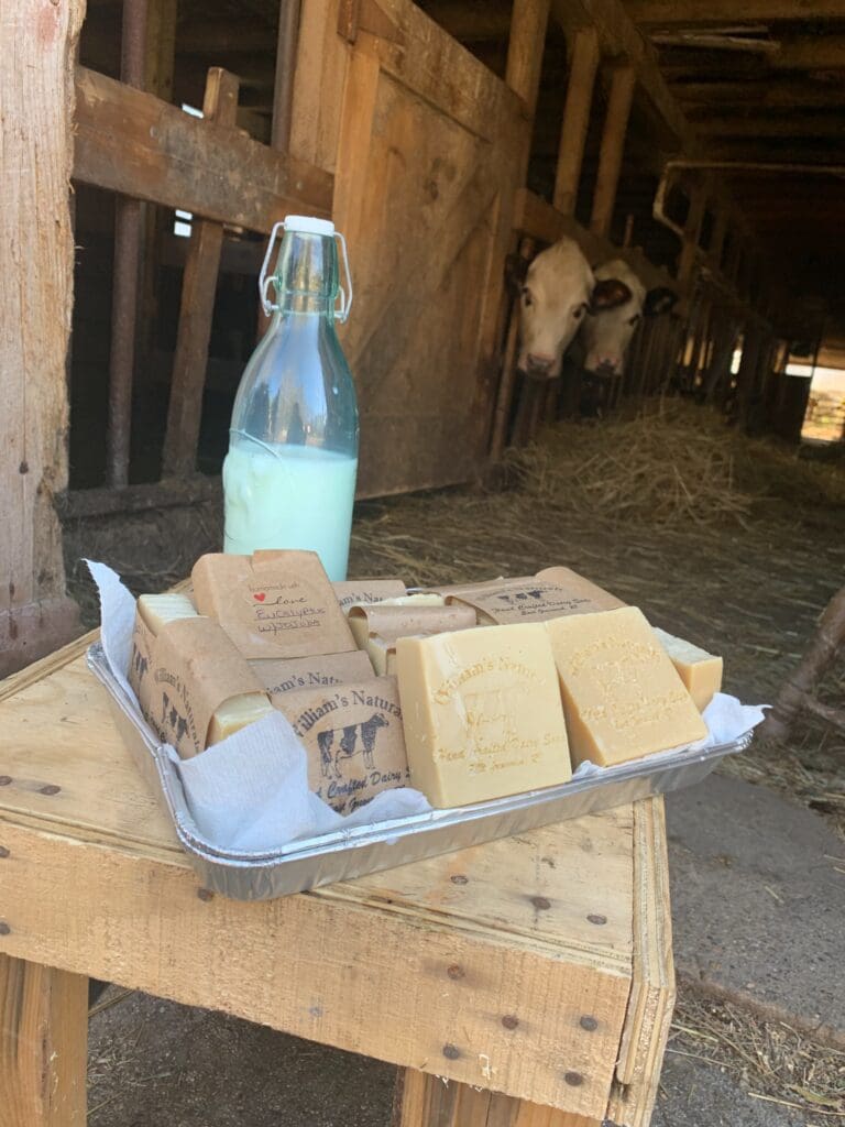 A tray of soap on a wooden table next to a bottle of milk.