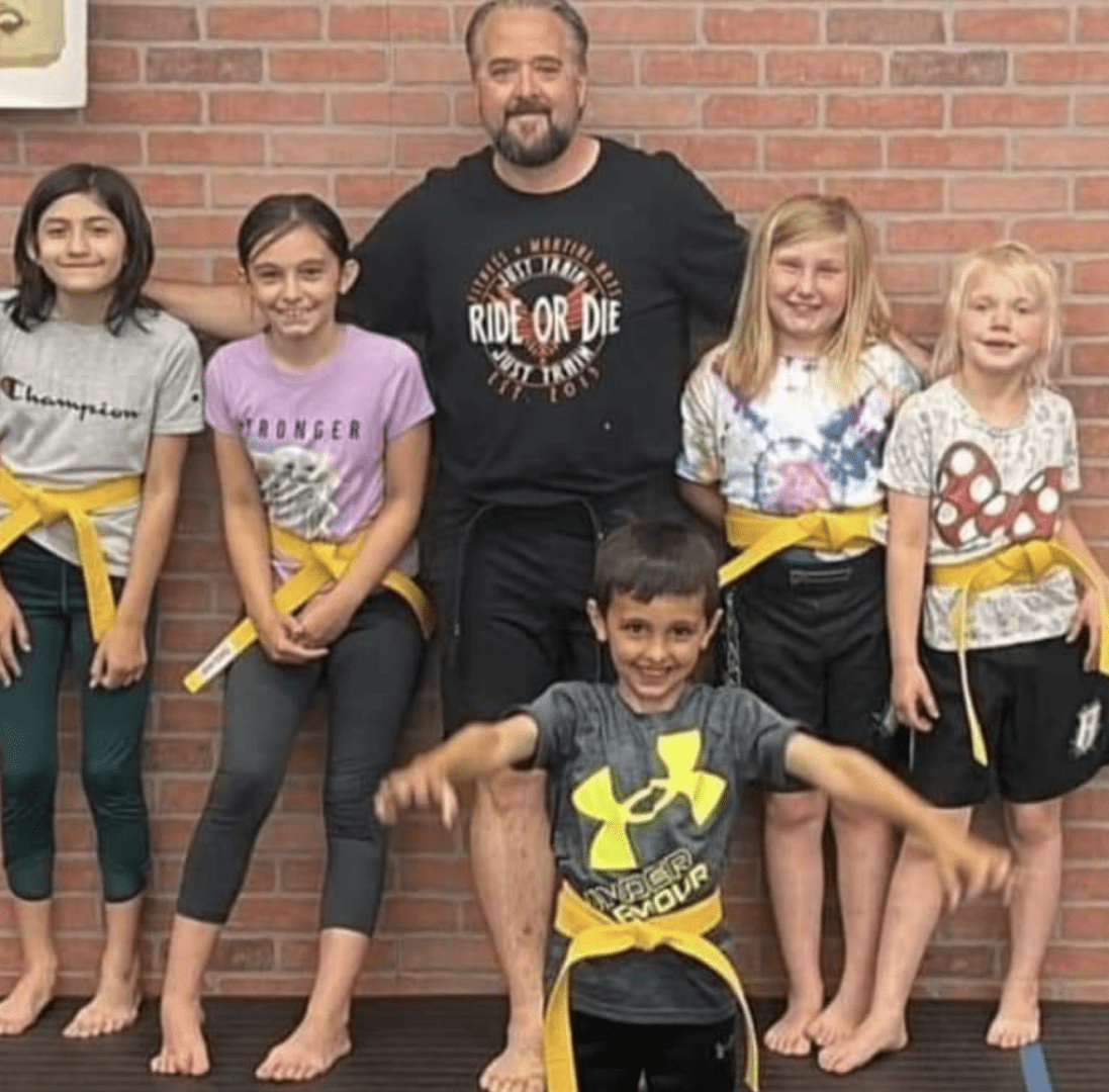 A group of children posing for a photo with a karate instructor.