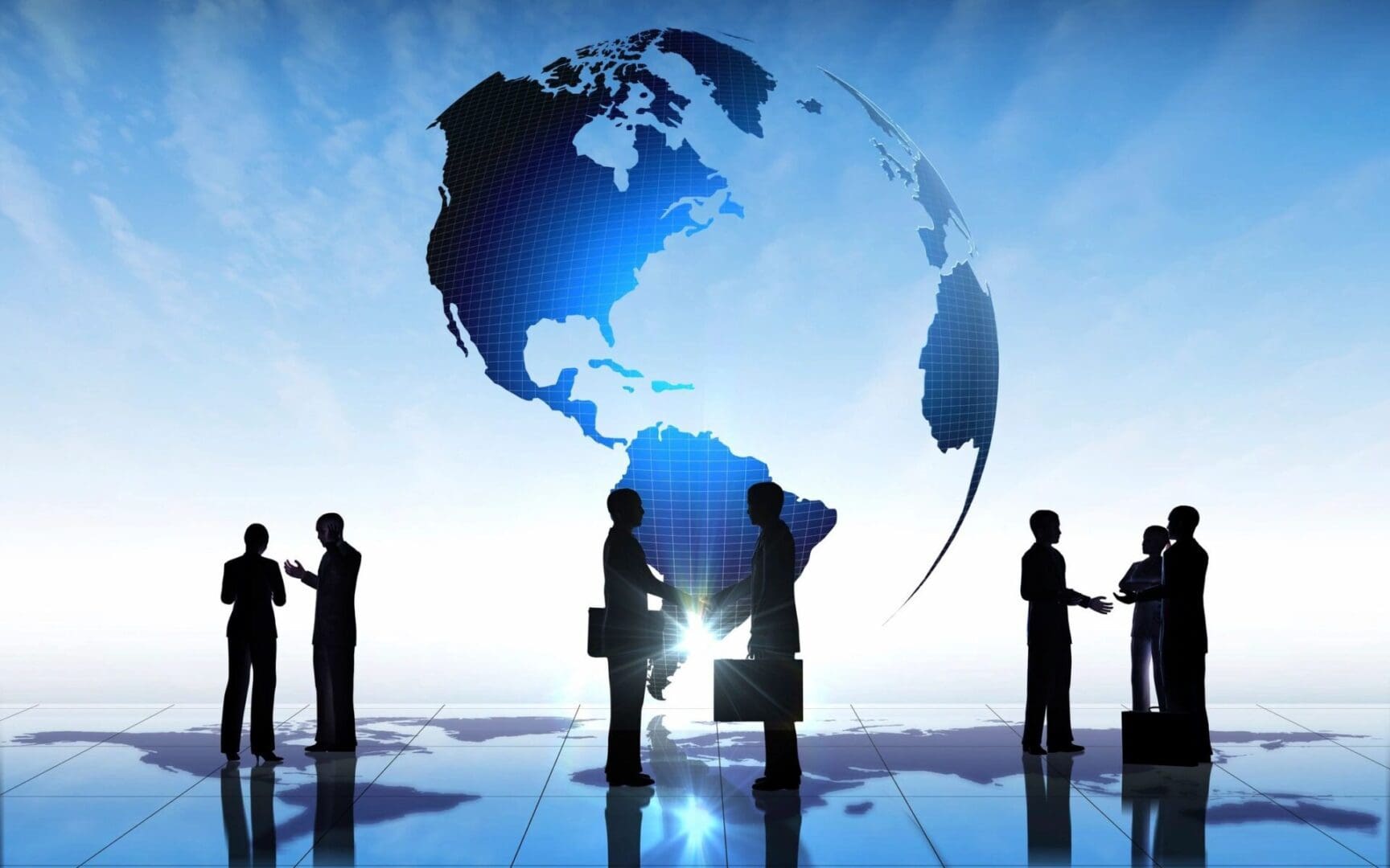 Silhouettes of business people standing in front of a globe.