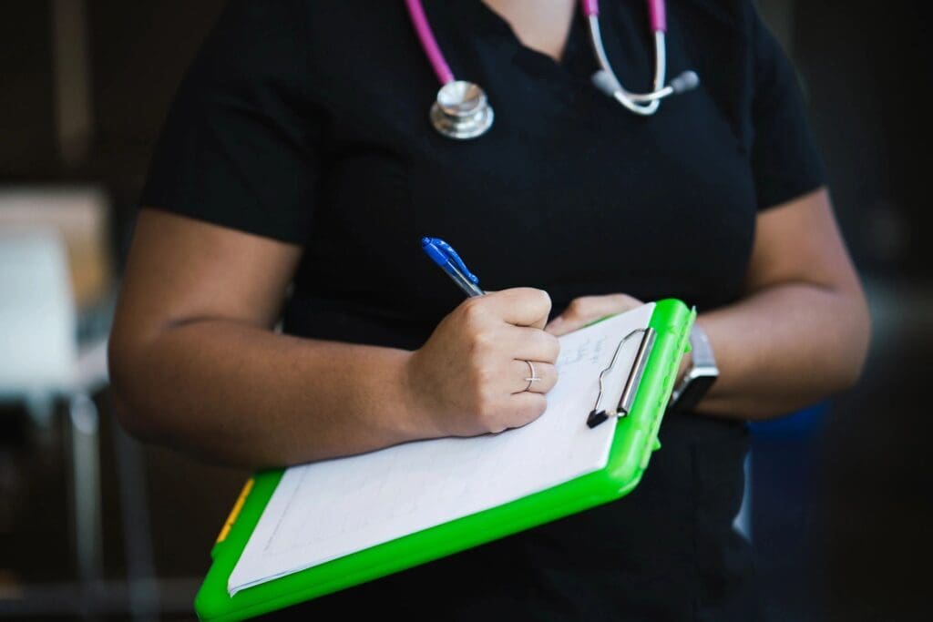 A nurse is holding a clipboard and writing on it.