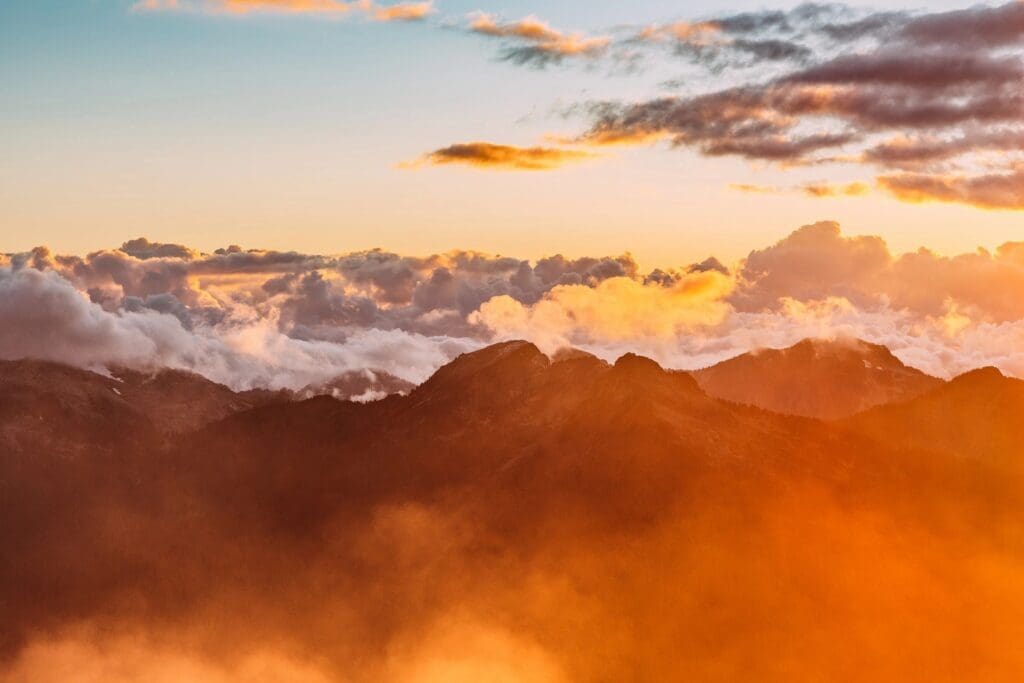 A sunrise over the mountains with clouds in the background.