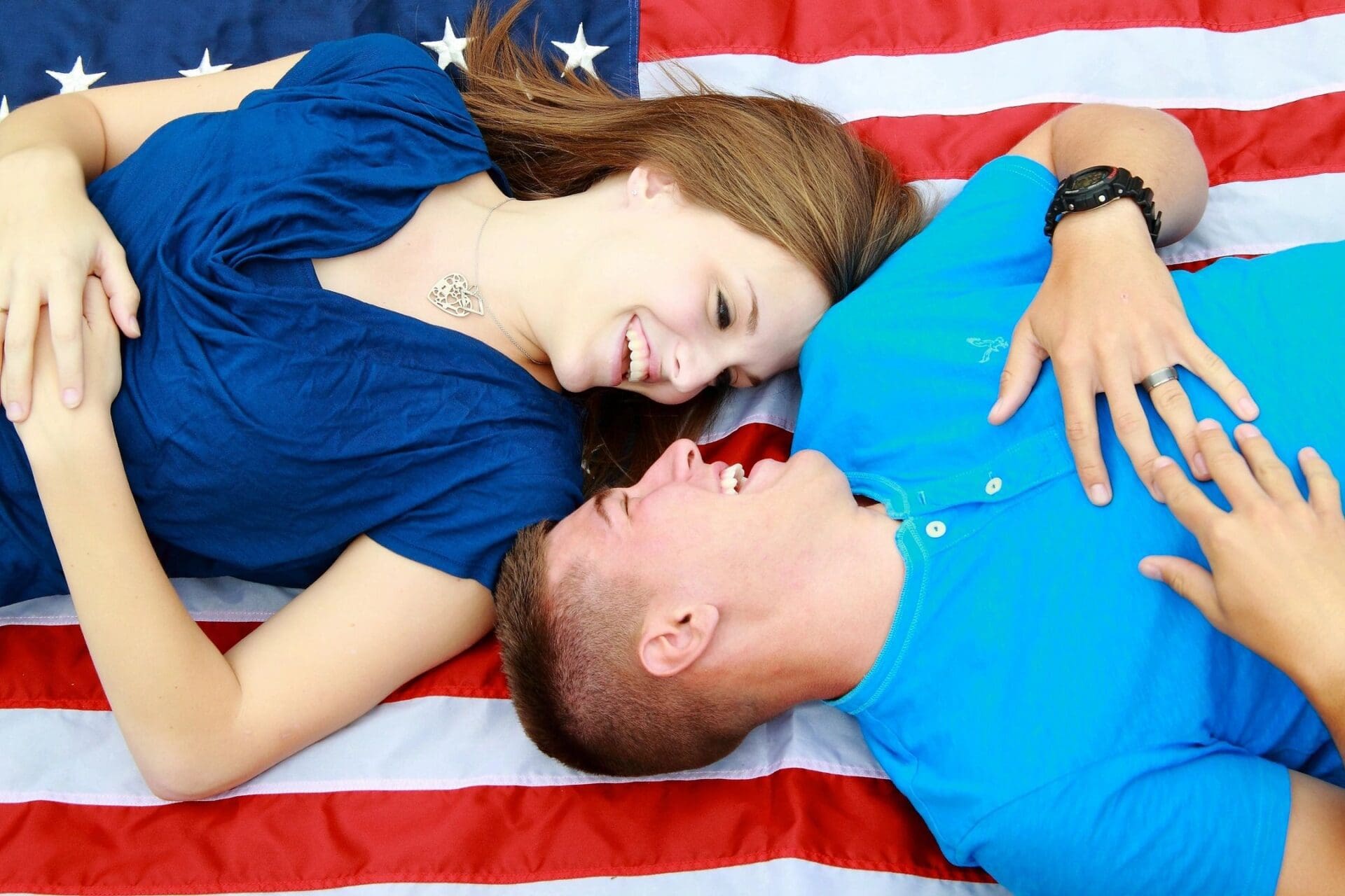 A man and woman laying on an american flag.