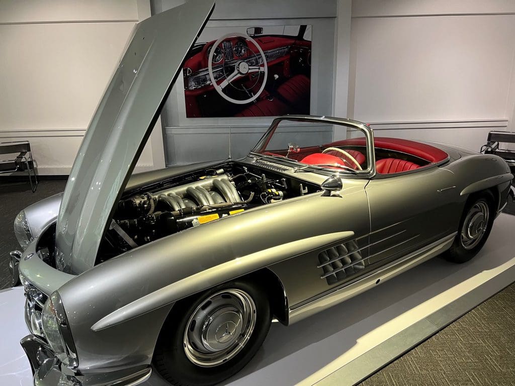 A silver mercedes benz sl roadster is on display in a showroom.