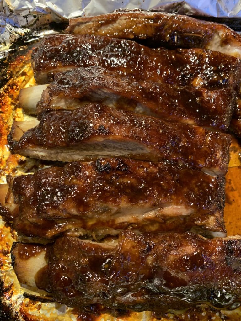 Bbq ribs in foil on a baking sheet.