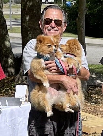 A man holding two small dogs at an event.