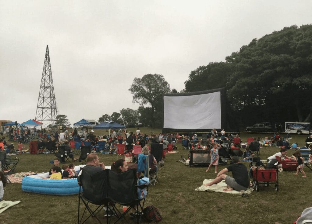 A group of people watching a movie in a field.