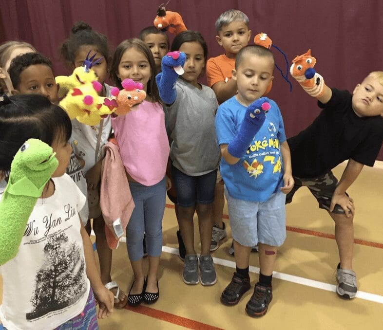 A group of children are posing with puppets.