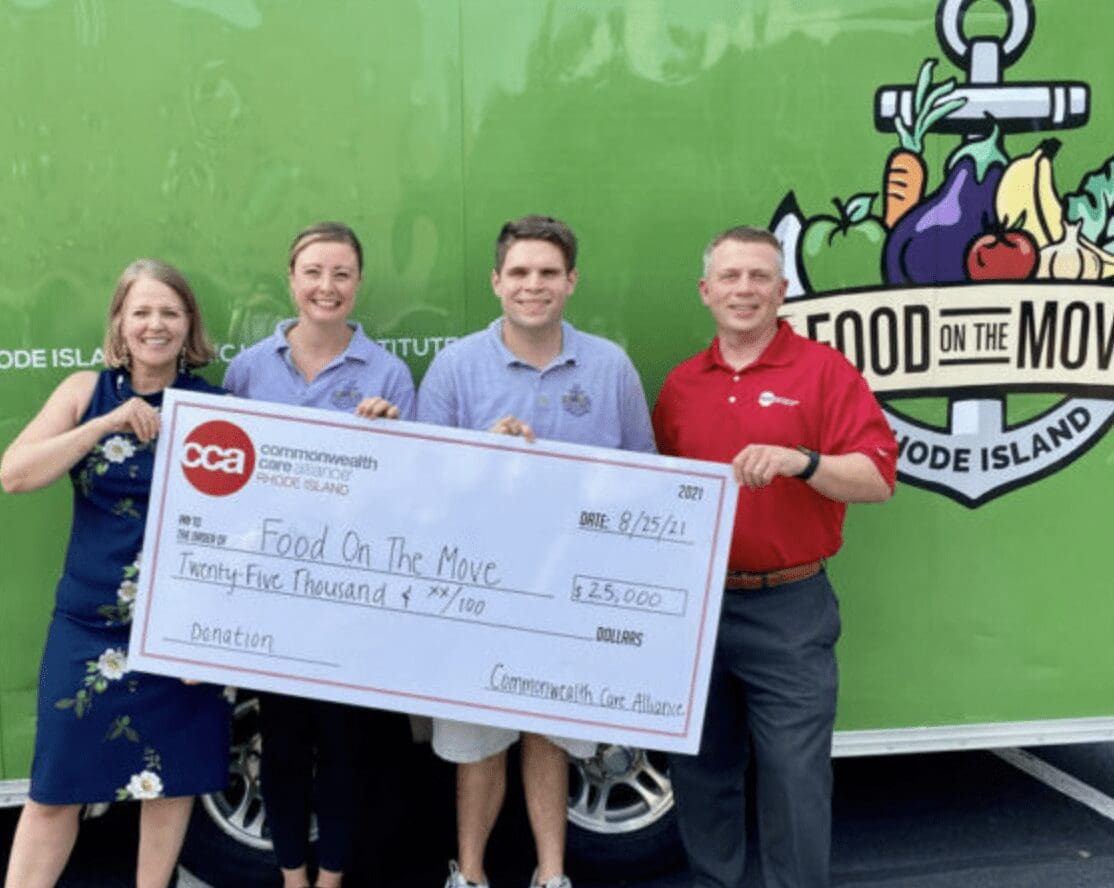 A group of people standing in front of a food truck with a check.