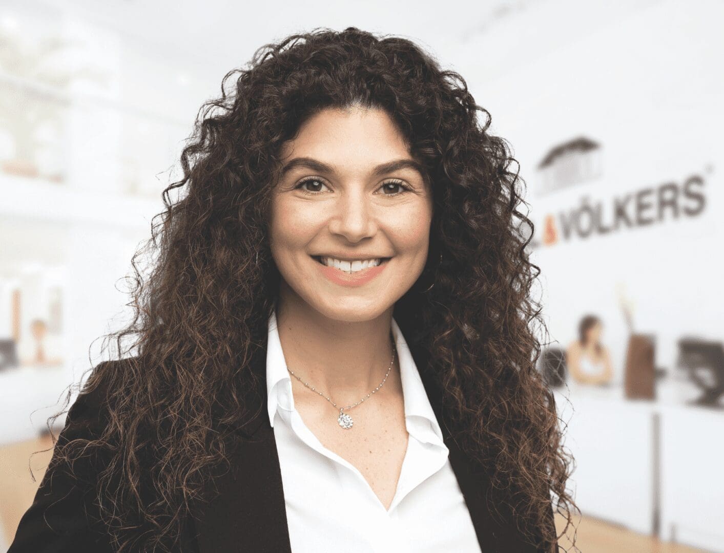 A woman with curly hair smiling in an office.