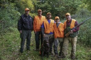 A group of hunters posing for a photo in the woods.