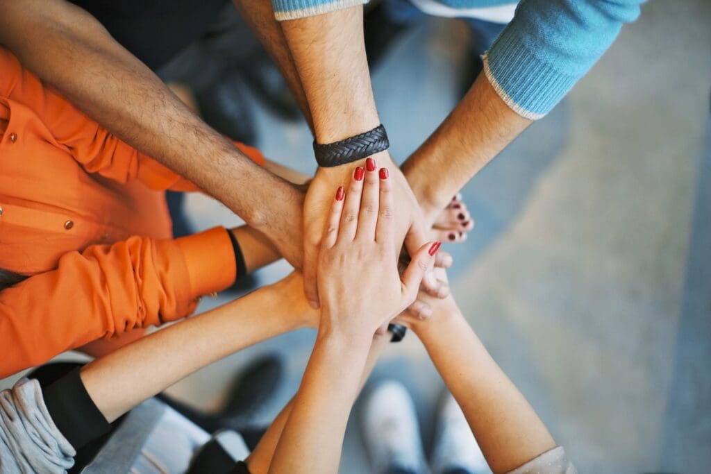 A group of people putting their hands together in a circle.
