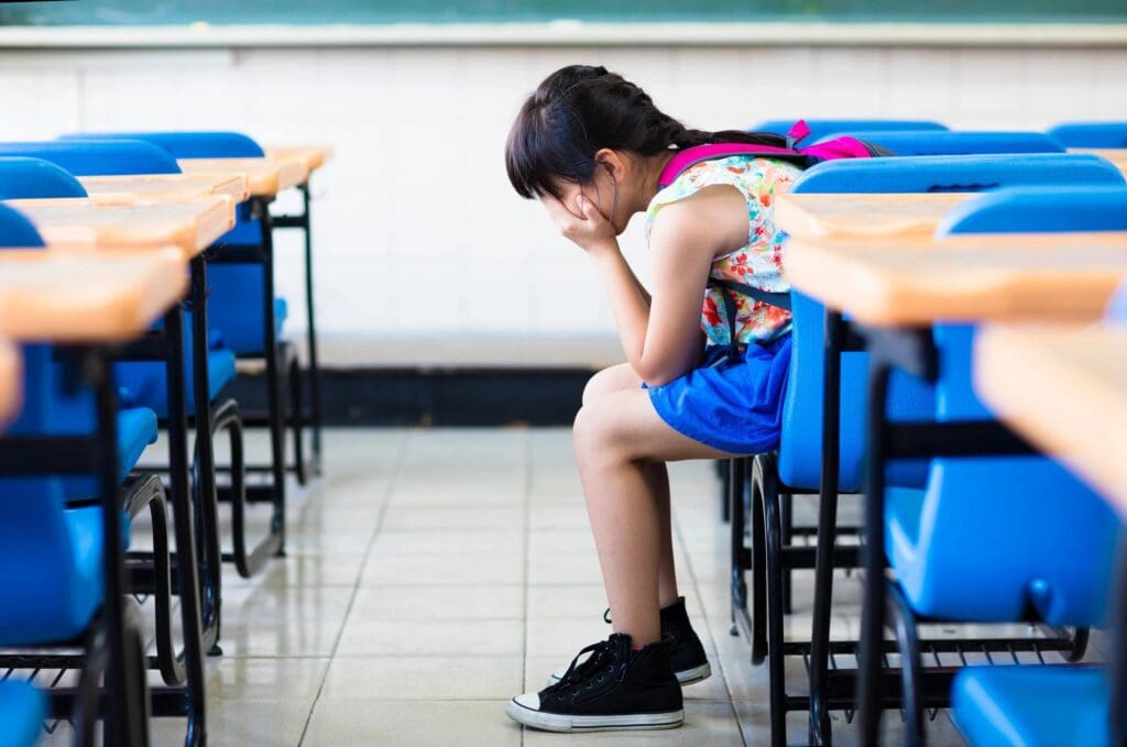 A young girl sitting in an empty classroom.