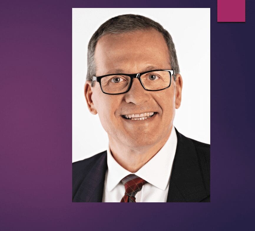 An image of a man with glasses and a purple background.
