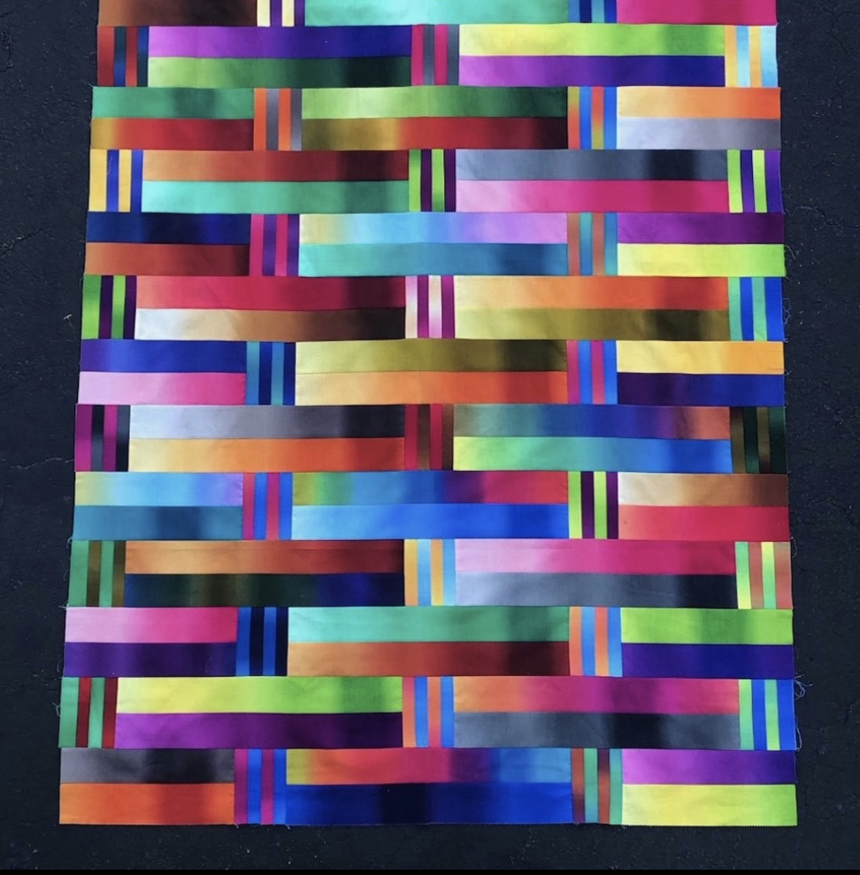 A quilt with colorful strips on a black background.