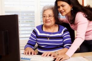 A woman and an older woman working on a computer.