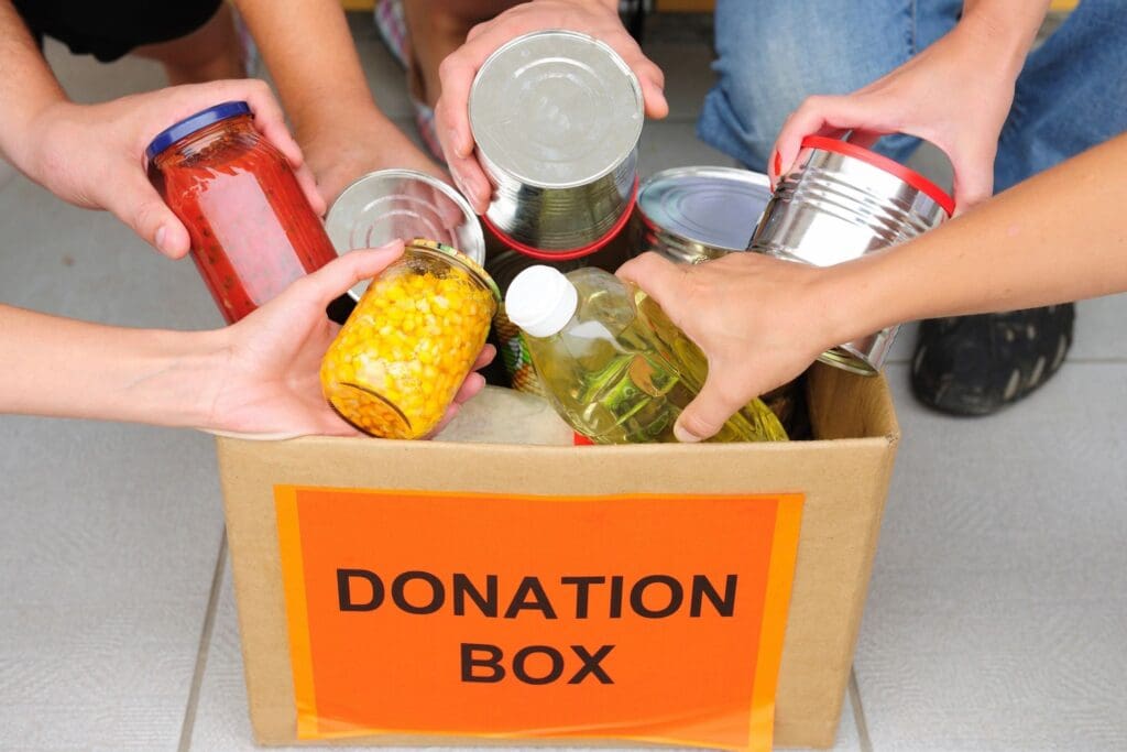A group of people putting food into a donation box.