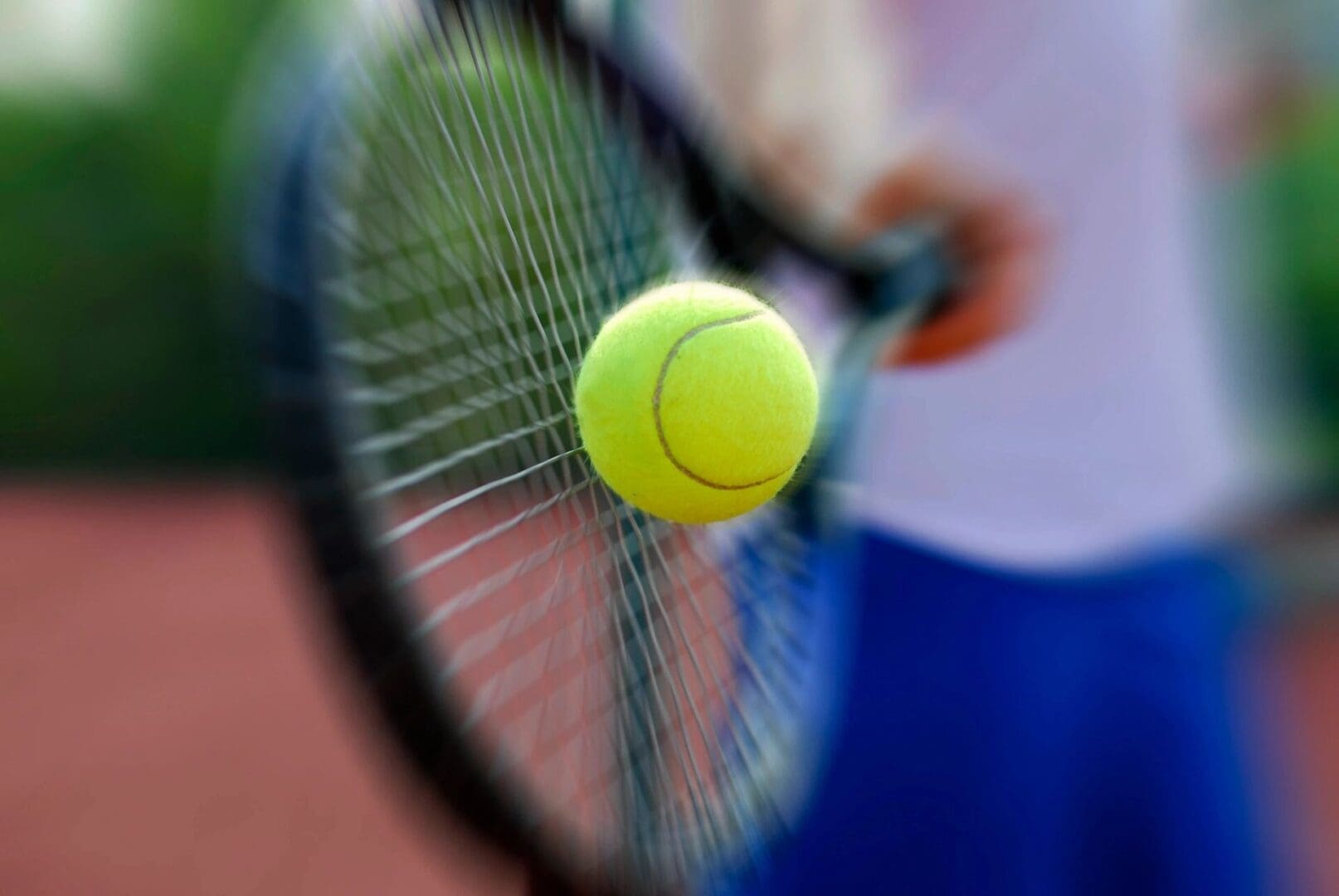 A person is holding a tennis racket and a ball.