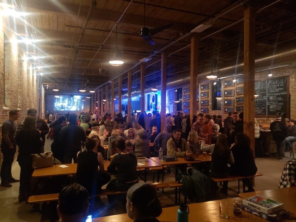 A crowd of people sitting at tables in a large warehouse.