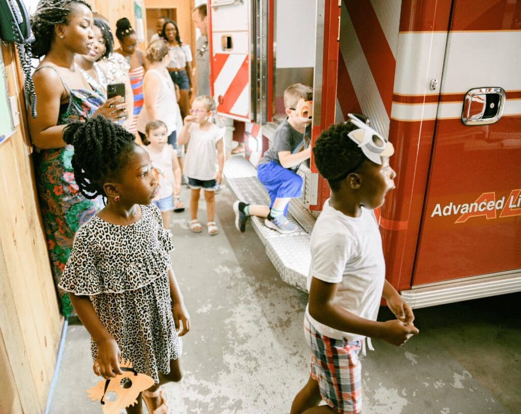 A group of children standing in front of a fire truck.