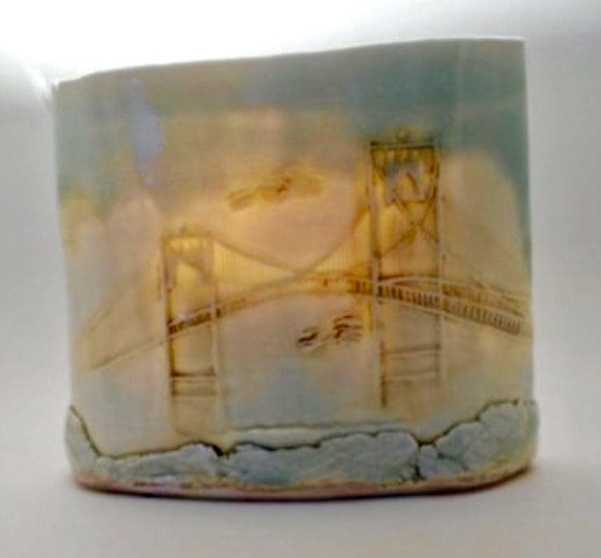 A ceramic mug with a drawing of a bridge.