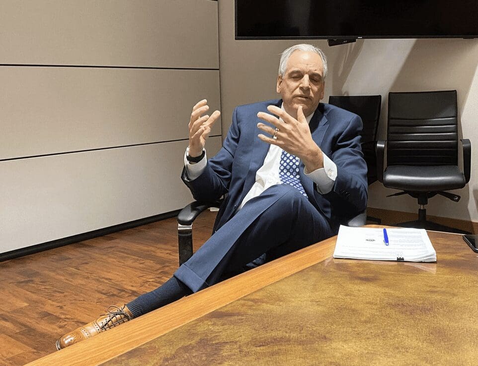 A man in a suit sitting in a conference room.