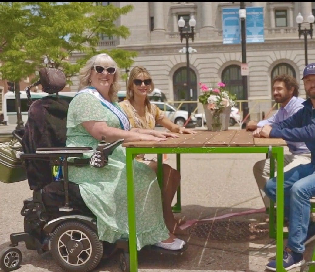 A group of people sitting around a table in a wheelchair.