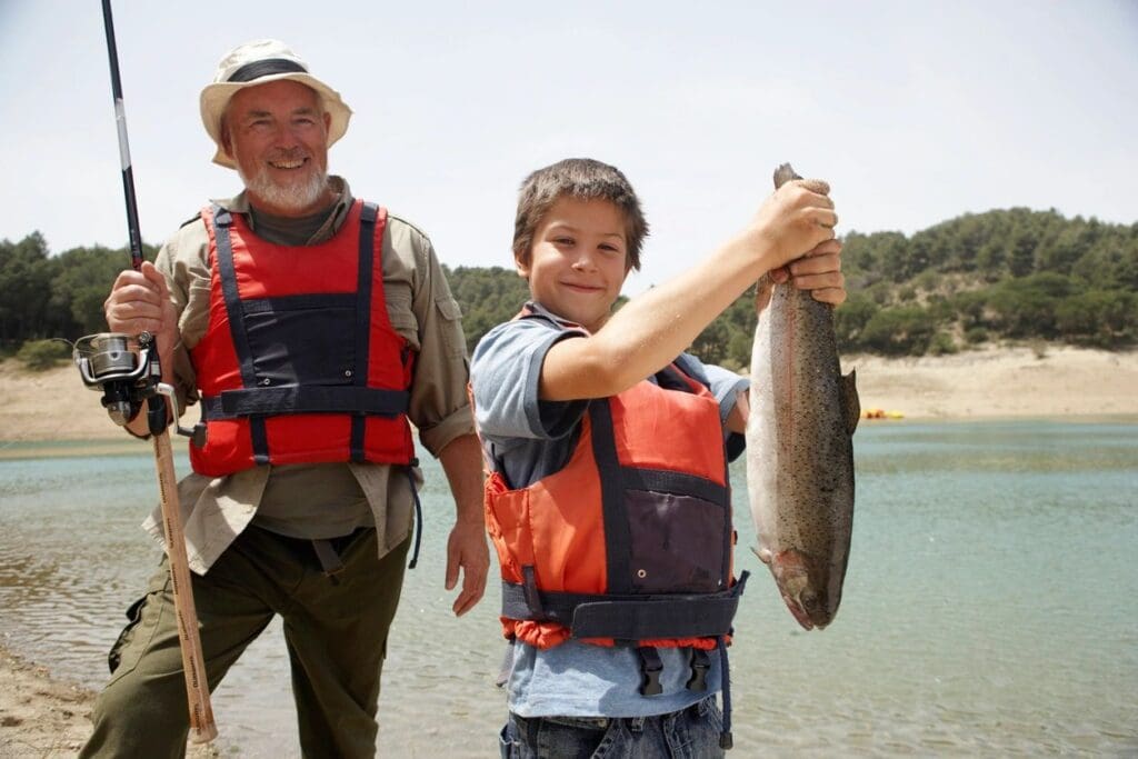 A man and a boy holding up a fish.