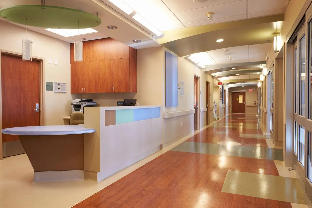 A hallway in a hospital with wooden floors.