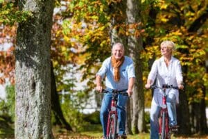 Senior couple riding bicycles in autumn park stock photo.