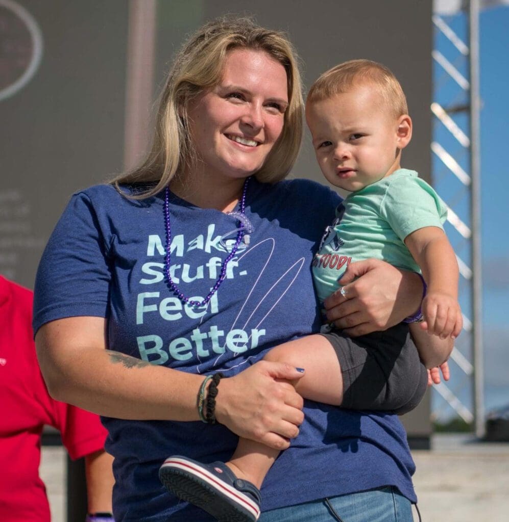 A woman holding a baby wearing a t - shirt that says make stuff feel better.