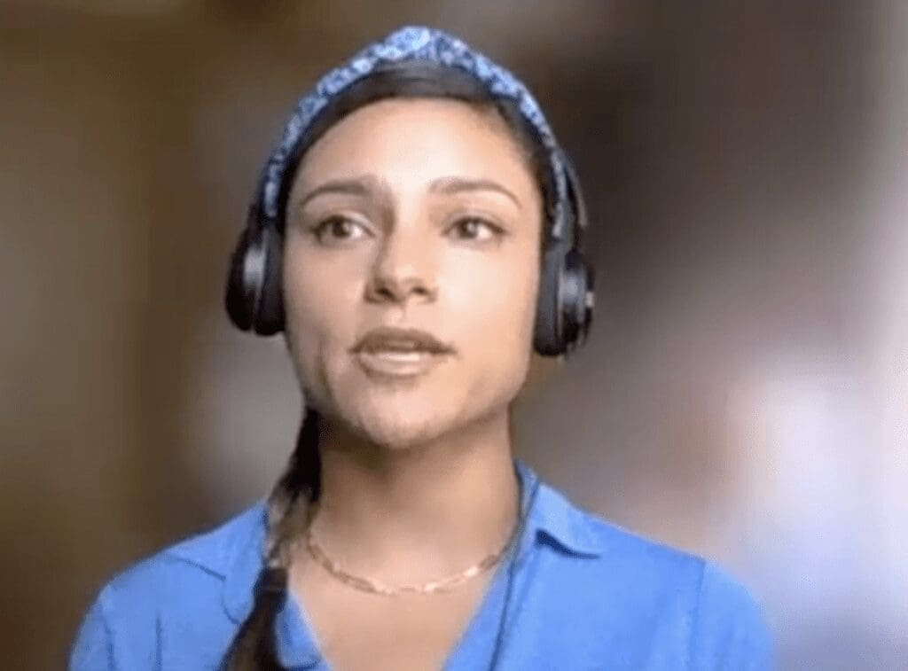 A woman in a blue shirt is wearing headphones.