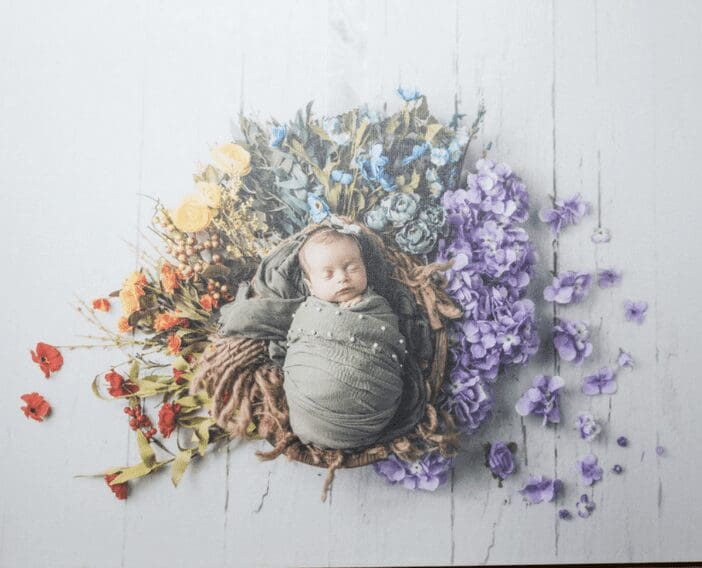 A baby is laying in a nest of flowers.
