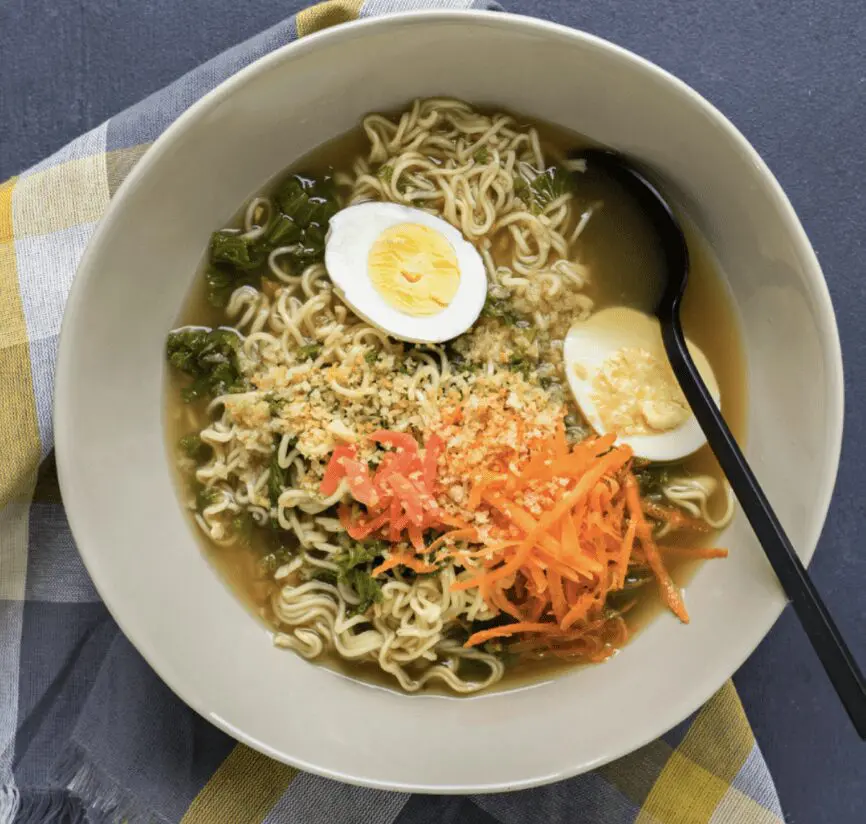 A bowl of ramen with an egg and vegetables.