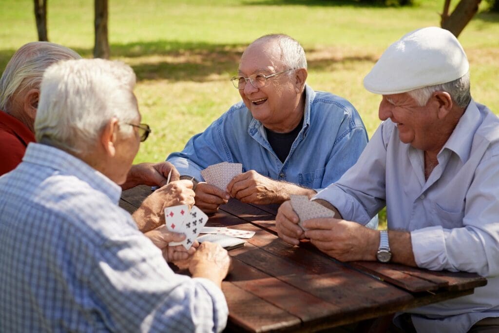 A group of older men playing cards in a park.