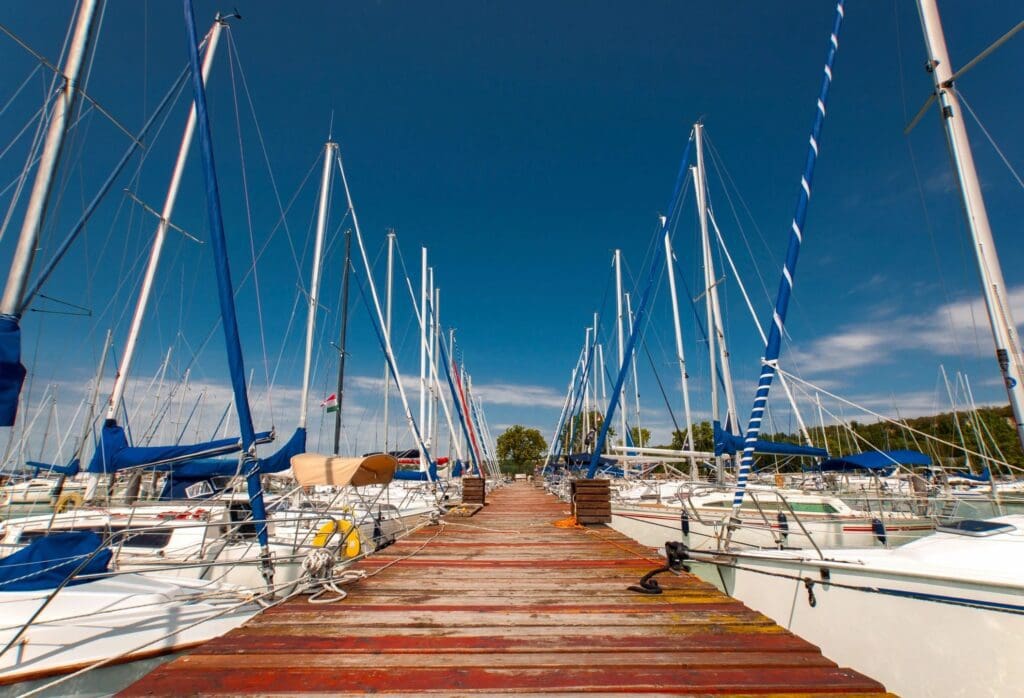 A wooden walkway leading to a marina full of sailboats.