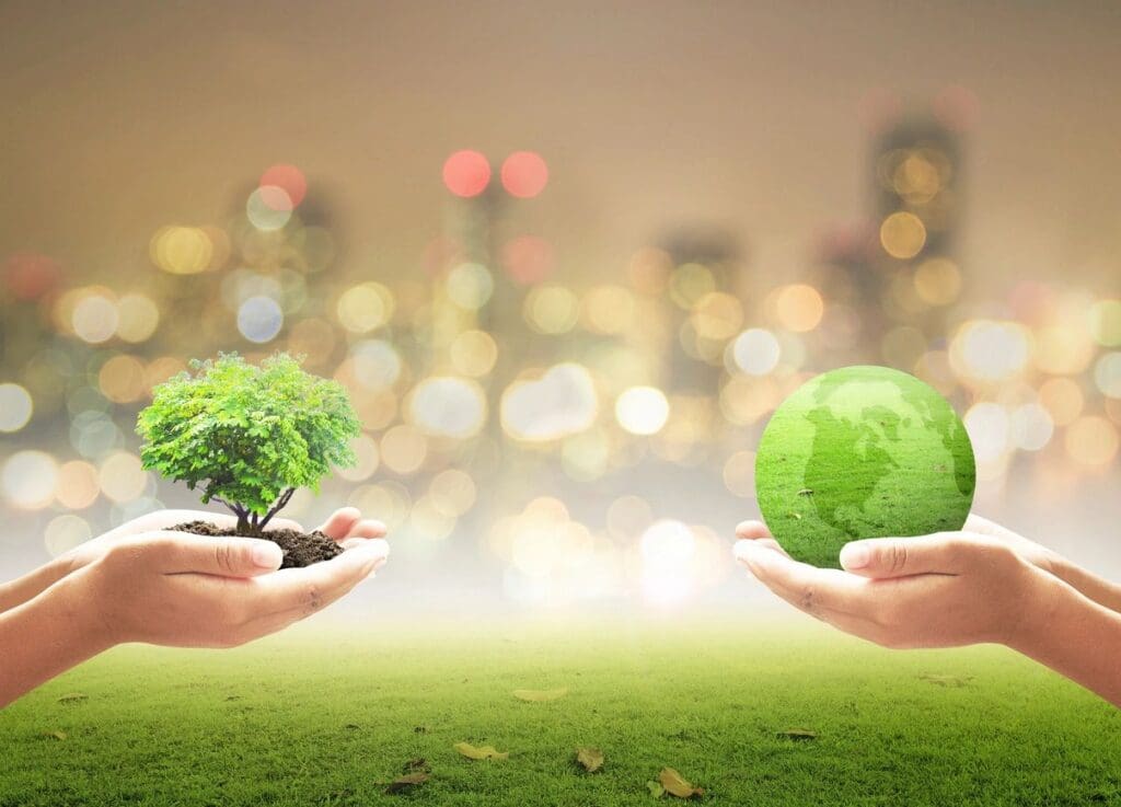 Two hands holding a green earth with a tree growing in it.