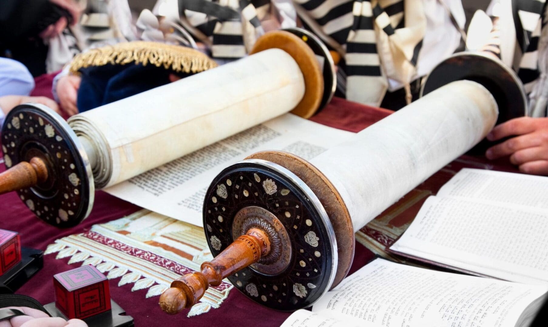 A group of people are sitting around a table with a torah.