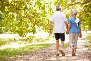 An older couple walking down a path in a park.