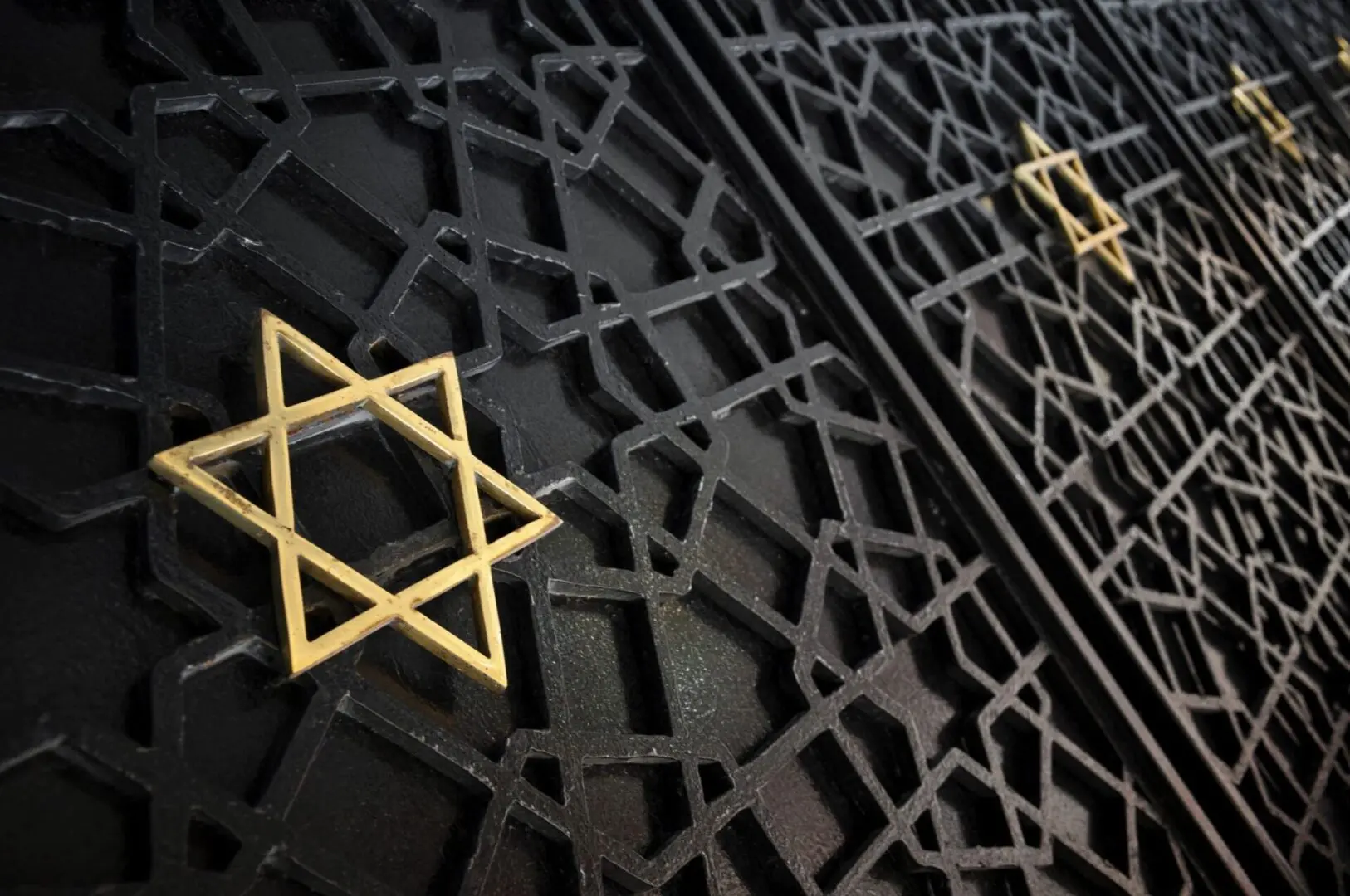 A golden star of david on a metal gate.