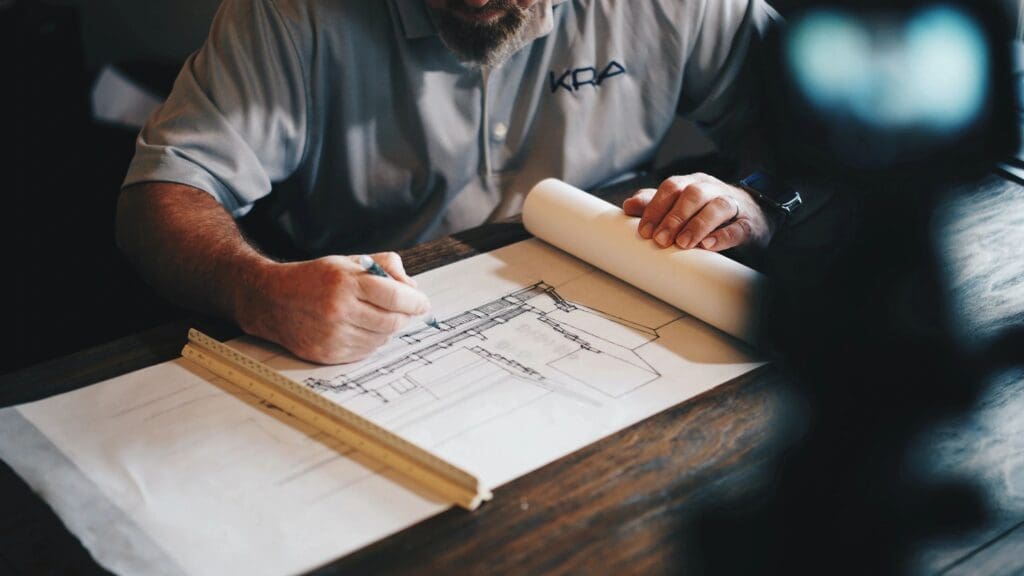 A man working on a blueprint at a table.