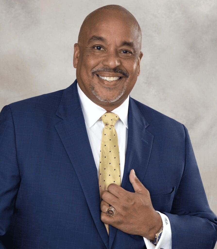 A black man in a suit and tie smiling.