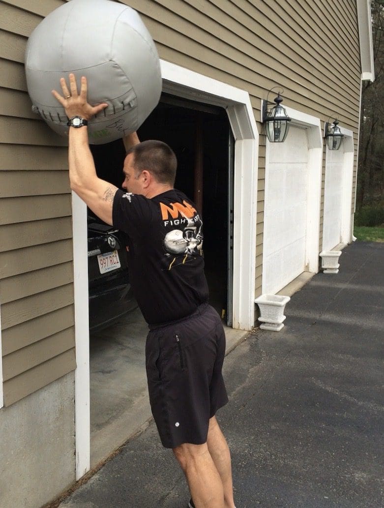 A man lifting an exercise ball out of a garage.