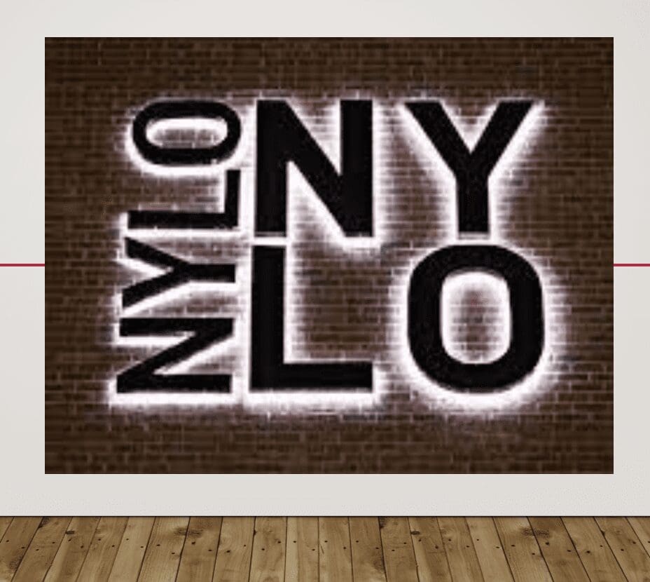 The word nylo is lit up in front of a brick wall.