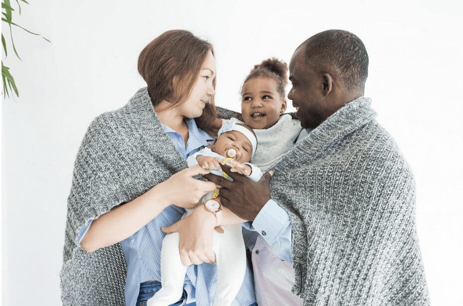 A family holding a baby wrapped in a blanket.