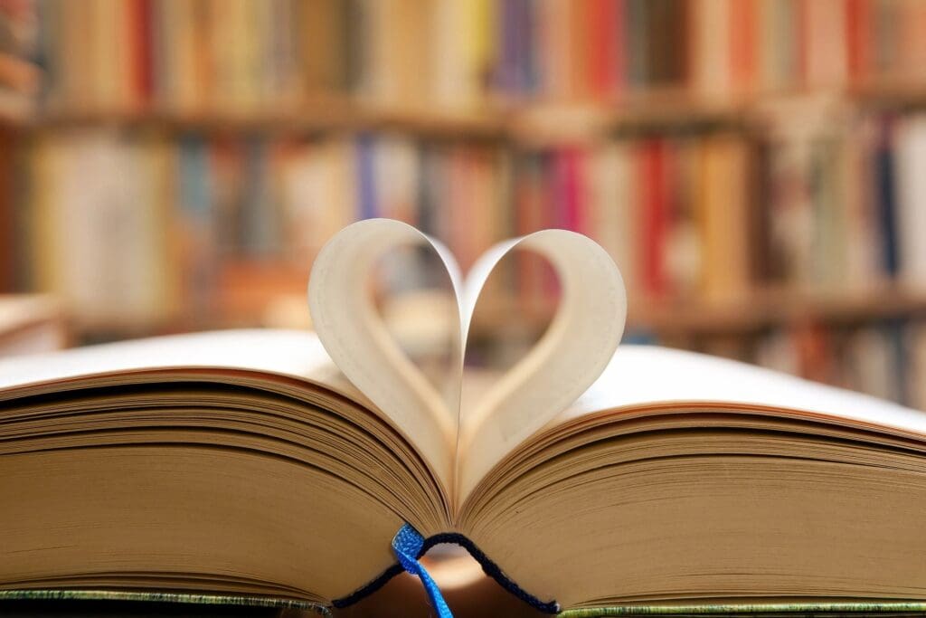 An open book with a heart cut out of it sitting on top of a bookshelf.