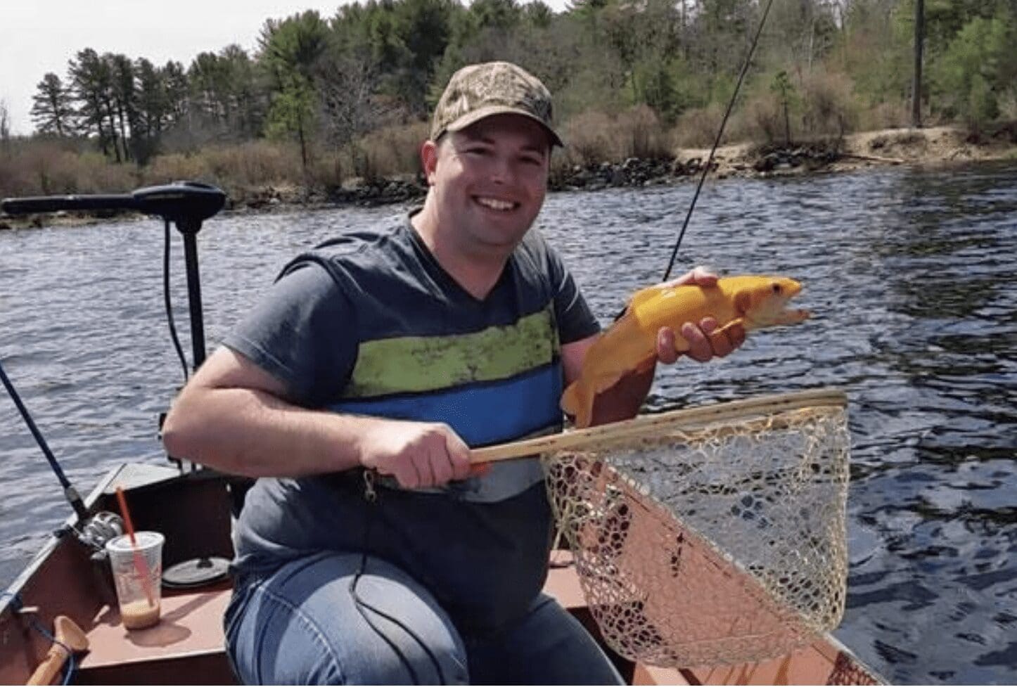 A man in a boat holding an orange fish.