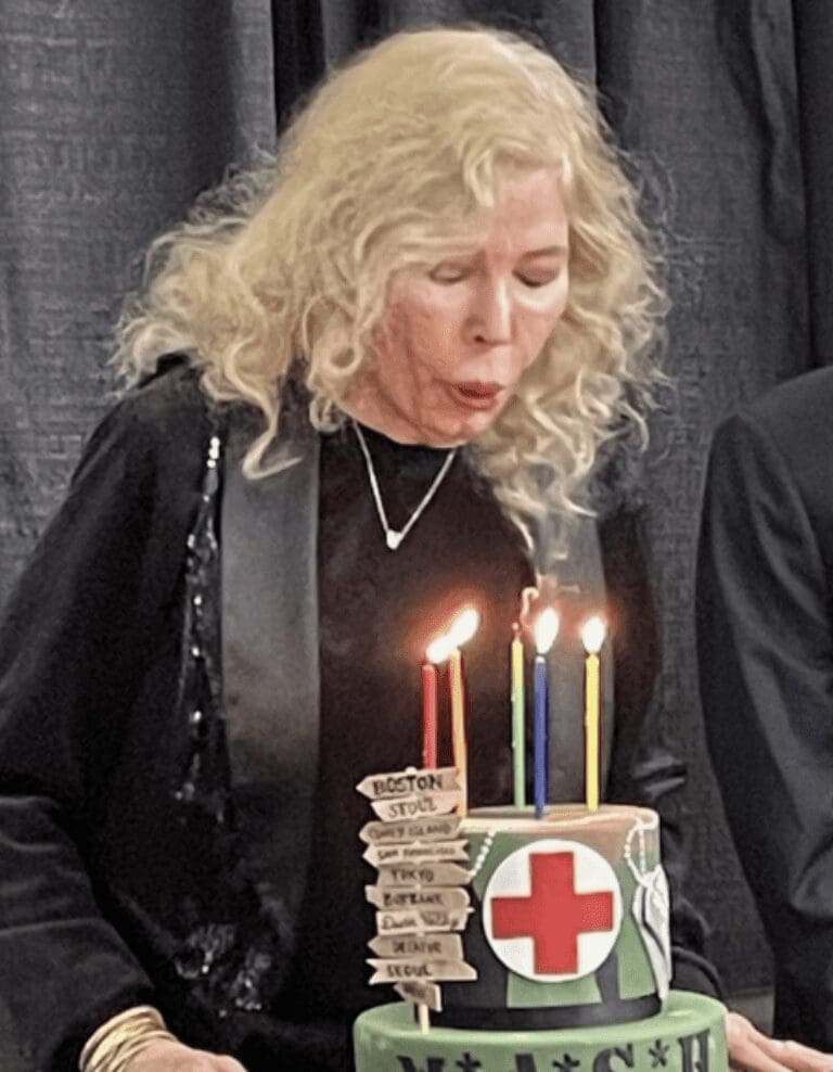 A woman blowing out candles on a birthday cake.