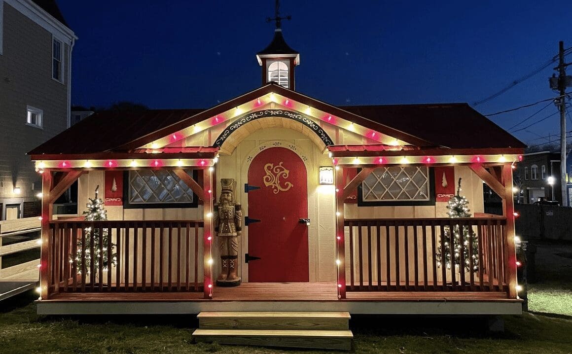 A red and white cottage with lights on the front porch.