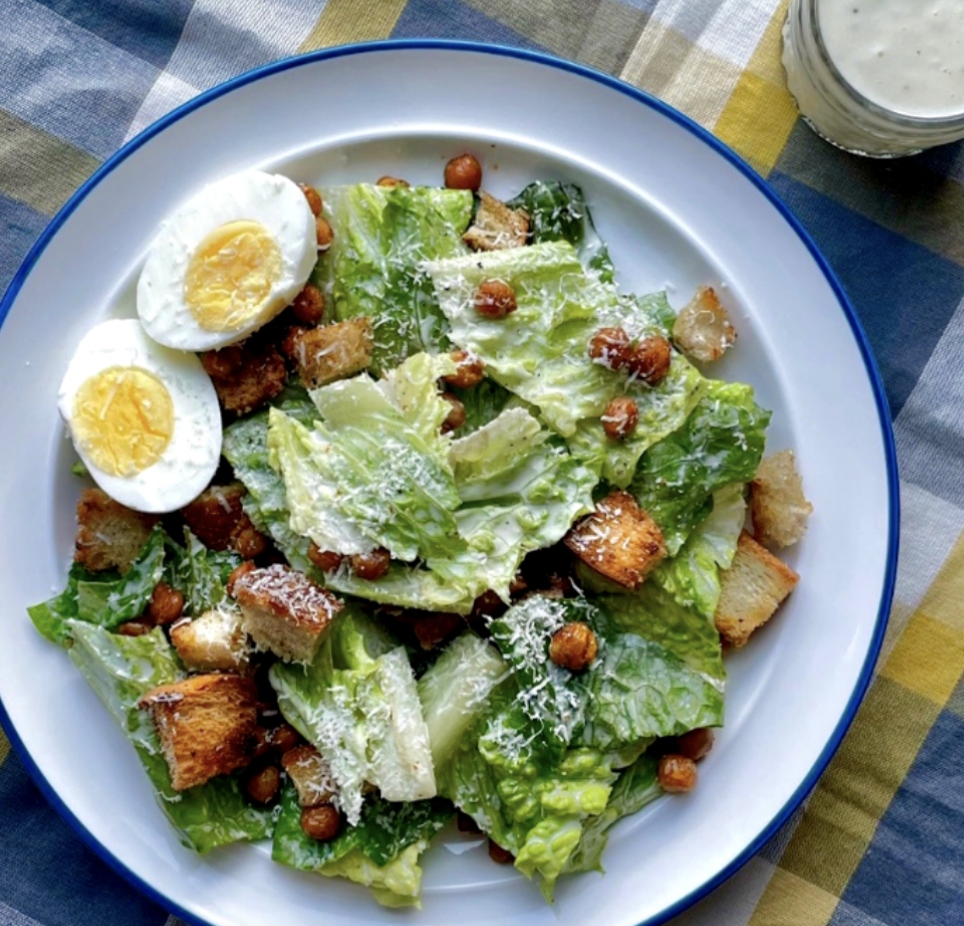 A plate of caesar salad with croutons and hard boiled egg.